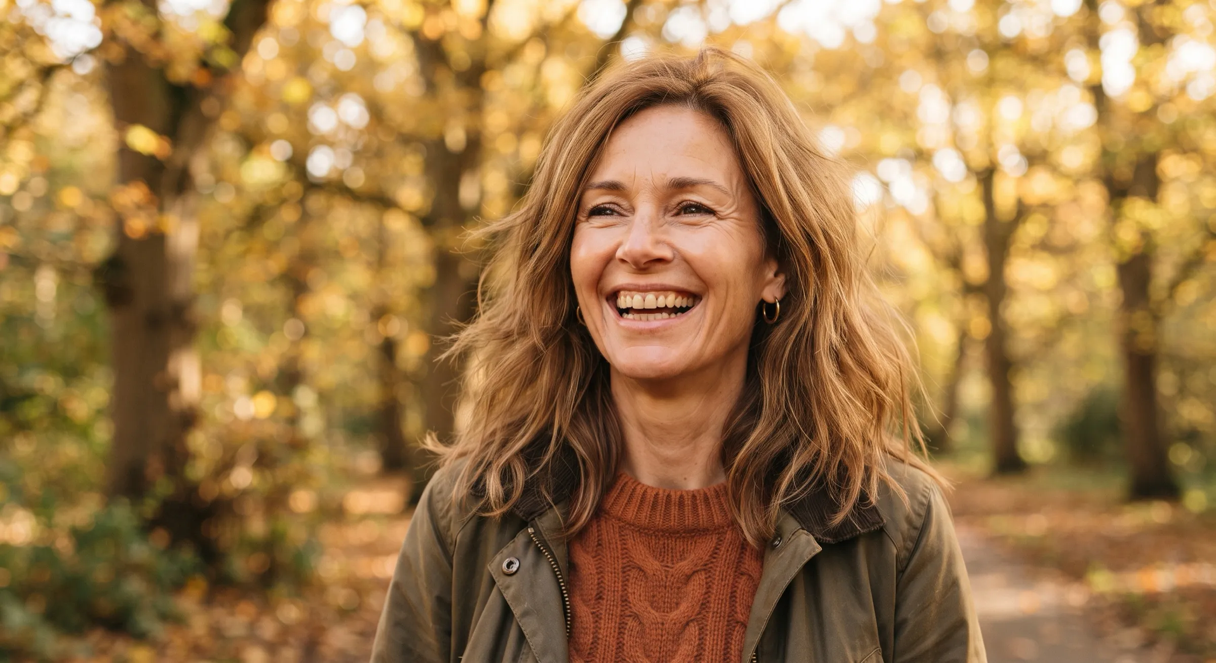 A woman laughing with a natural, healthy smile on a fall afternoon